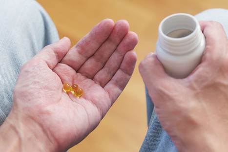 An image of someone holding vitamin D3 capsules